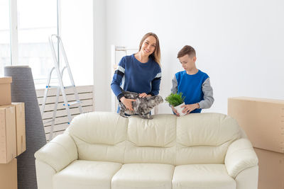 Portrait of mother with son standing by sofa at home