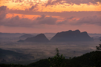 Scenic view of silhouette mountains against orange sky