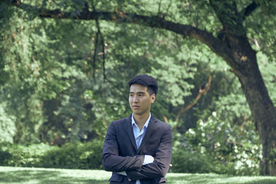 Portrait of young man standing against trees