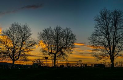 Silhouette trees against dramatic sky during sunset