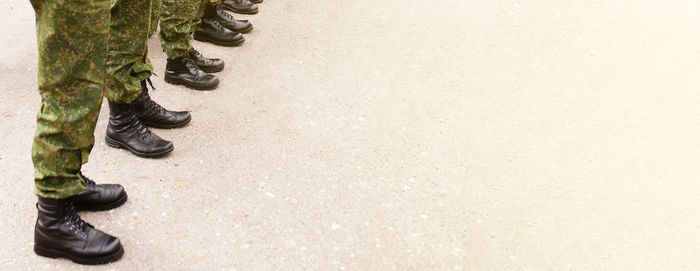 Army soldiers in camouflage uniforms and footwear boots in a resting position, standing in line