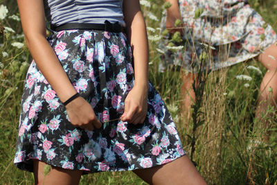 Midsection of woman wearing floral patterned skirt while standing on land