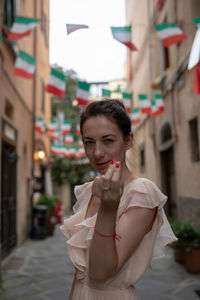 Beautiful woman gesturing while standing amidst buildings