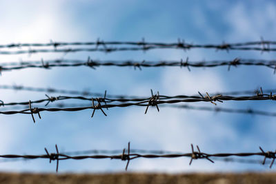 Low angle view of barbed wire fence against sky