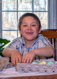 Smiling boy proudly shows off his colorful easter eggs he just dyed