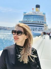 Portrait of young woman wearing sunglasses against sea