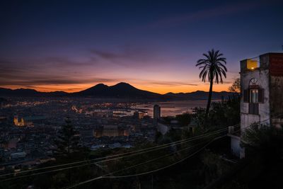 High angle view of city by mountains against sky during sunset