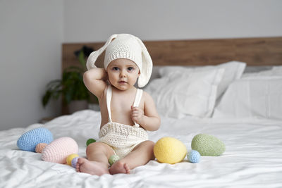 Portrait of cute girl sitting on bed at home