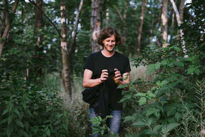 Young woman photographing through camera in forest