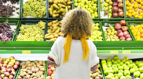 Rear view of woman holding fruits for sale at market stall