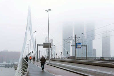 Rear view of people walking on bridge during foggy weather