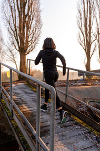 Young adult woman is running on a ship gangway in the morning - concept of health and wellness