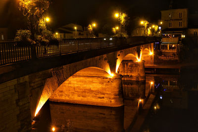 Illuminated bridge over canal in city at night