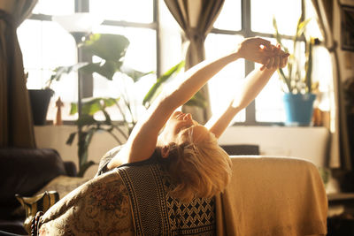 Woman stretching while leaning on sofa