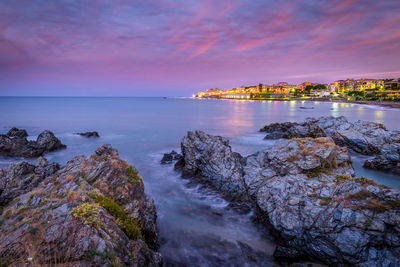 Rocks at sea shore against sky during sunrise