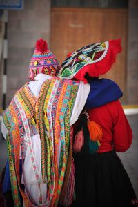 Rear view of female friends in traditional clothing standing on footpath