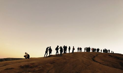 People on sand in desert against sky