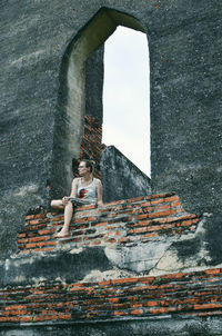 Low section of woman sitting on wall