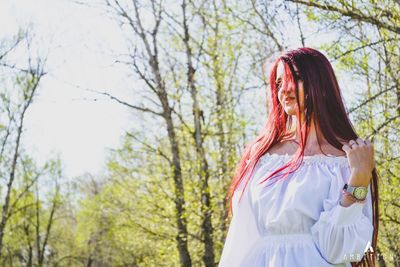 Young woman standing against trees in park