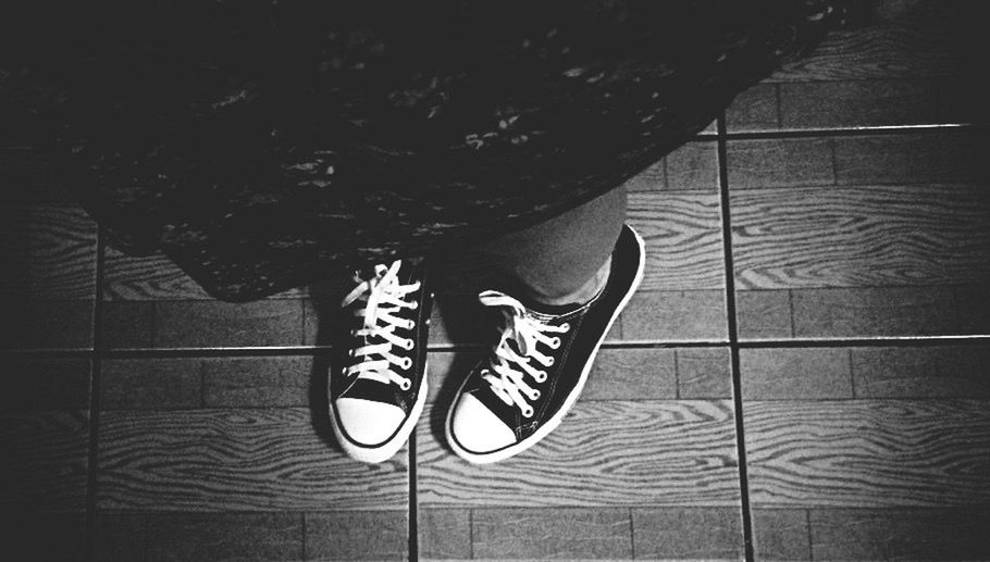 indoors, shoe, one person, close-up, high angle view, low section, pattern, footwear, person, part of, shadow, black color, design, day, standing, flooring, wall - building feature