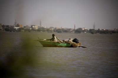 Boat in river with city in background