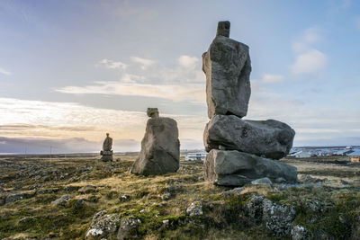 Stacked stones on field against sky