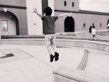 Rear view of man jumping on tiled floor