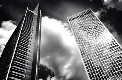 Low angle view of skyscrapers against cloudy sky