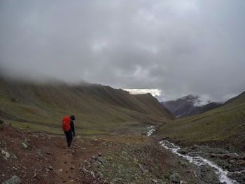 Rear view of man walking on mountain against sky