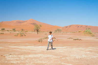 Hiker walking in namib desert against clear sky during sunny day