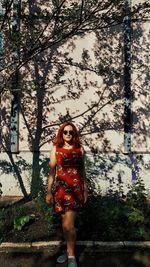 Portrait of a young woman standing against trees