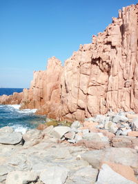 Rock formations by sea against clear blue sky