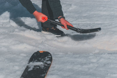 A close-up shot of a caucasian man shoveling snow at a ski resort