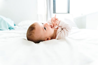 Close-up of baby lying down on bed at home