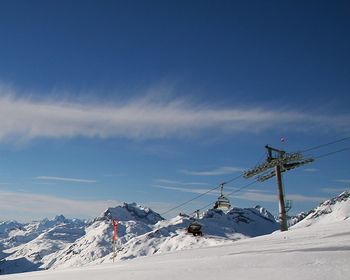 Scenic view of snow covered mountains against blue sky