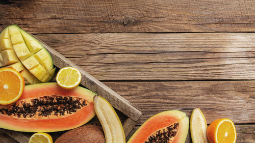 Fresh tropical fruits in a wooden delivery box on a wooden background. papaya, orange, banana