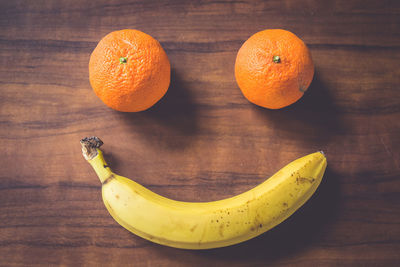 Smiley face made of oranges and banana on table