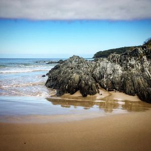 Scenic view of rocks on beach against sky