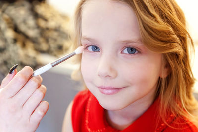 Close-up of young woman applying make-up