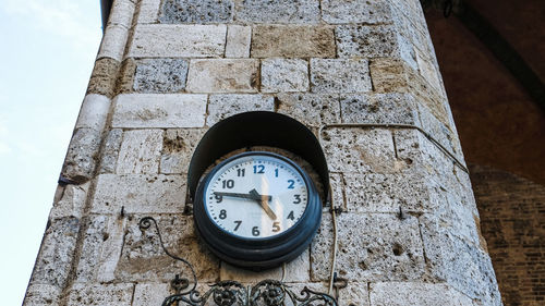 Low angle view of clock on wall against building