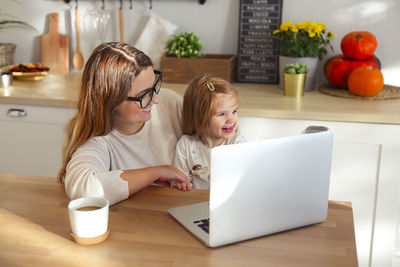 Mother and daughter looking at laptop while sitting at home