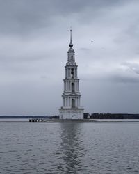 Lighthouse by sea against sky