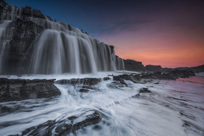 Scenic view of waterfall against sky