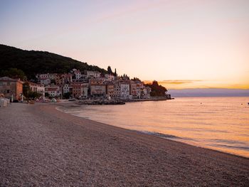 Town by sea against sky at sunset