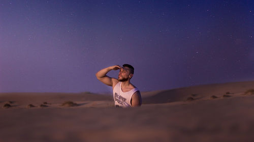 Woman standing on sand dune in desert against sky