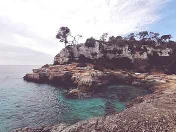 Rock formations by sea against sky