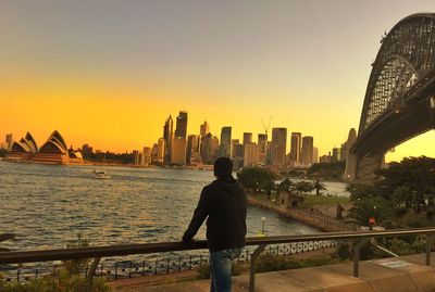 Rear view of man standing sydney harbor bridge at sunset