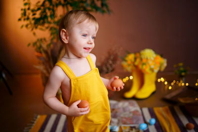 Baby with easter eggs in yellow jumpsuit