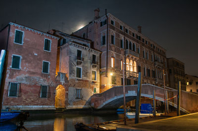 Canal by illuminated buildings against sky at night