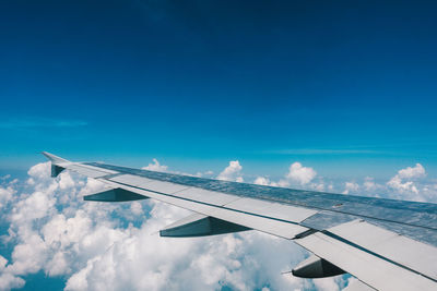 Low angle view of airplane wing against blue sky